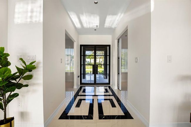 Step into elegance with this stunning entryway featuring sleek black-framed glass doors and striking custom tile inlay flooring—setting the tone for a home that blends modern design with timeless sophistication. | Image 36