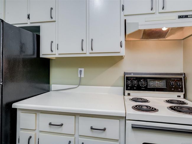 Kitchen featuring white electric stove, freestanding refrigerator, premium range hood, light countertops, and white cabinets | Image 11