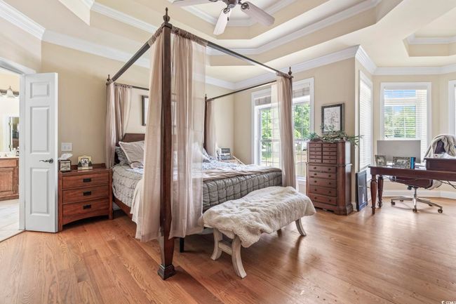 Bedroom featuring multiple windows, light wood-type flooring, ornamental molding, and a raised ceiling | Image 13