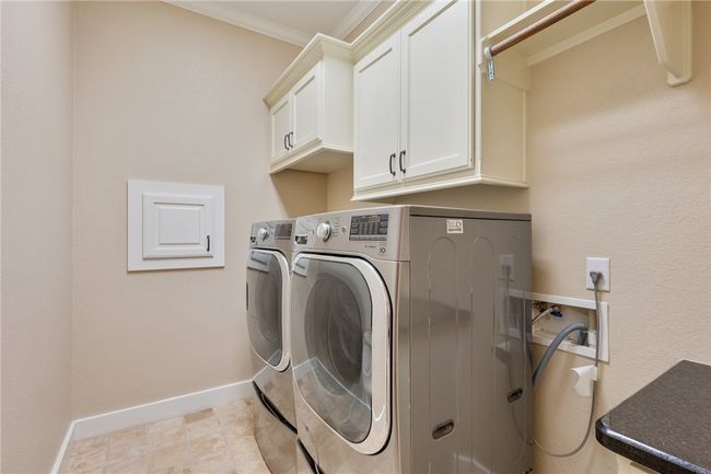 Washroom featuring washing machine and clothes dryer, cabinet space, crown molding, and baseboards | Image 10