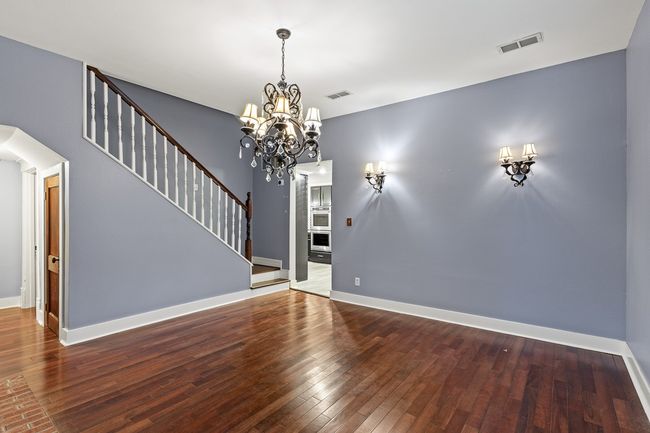Unfurnished living room with hardwood / wood-style flooring, a chandelier, stairs, and baseboards | Image 15