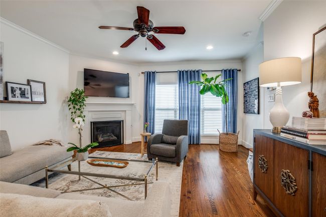 Living area with a ceiling fan, crown molding, wood finished floors, a glass covered fireplace, and recessed lighting | Image 6