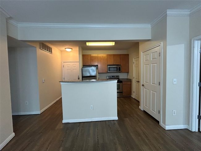 Kitchen featuring visible vents, baseboards, dark wood-style floors, appliances with stainless steel finishes, and ornamental molding | Image 21