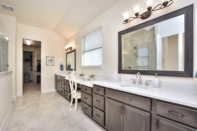 Full bathroom with a spacious closet, visible vents, vaulted ceiling, tiled shower, and vanity | Image 23