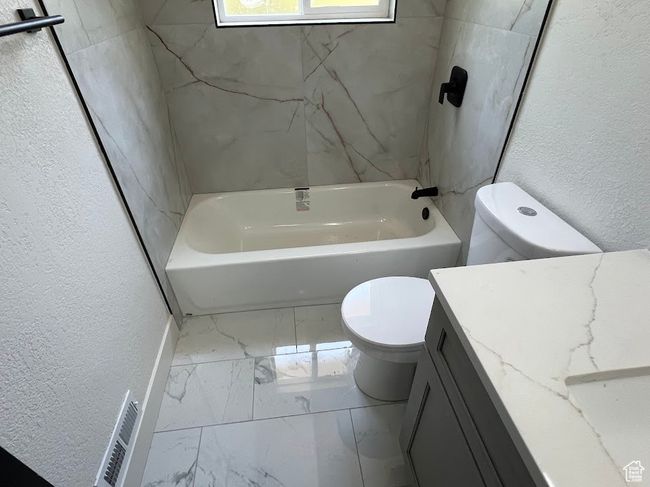 Bathroom featuring marble finish flooring, a textured wall, vanity, and shower combination | Image 18