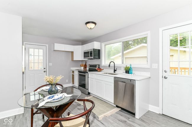 kitchen with stainless steel appliances, a sink, baseboards, and light countertops | Image 9