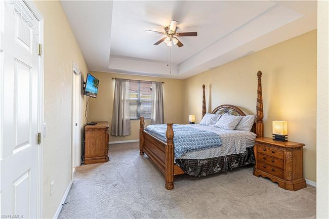 Carpeted bedroom featuring a tray ceiling, ceiling fan, and baseboards | Image 16