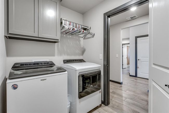 Clothes washing area featuring cabinet space, washer and clothes dryer, visible vents, and light wood-style floors | Image 8