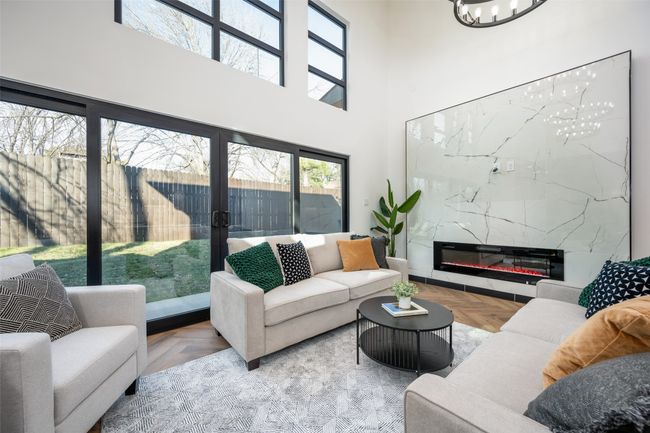 Living area with a chandelier, a towering ceiling, a high end fireplace, and french doors | Image 16