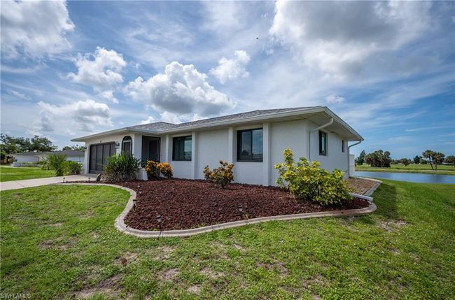 Single story home with driveway, stucco siding, an attached garage, a water view, and a front yard | Image 35