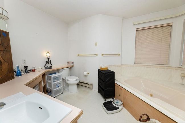 Bathroom featuring a whirlpool tub, a baseboard heating unit, toilet, and tile patterned floors | Image 22