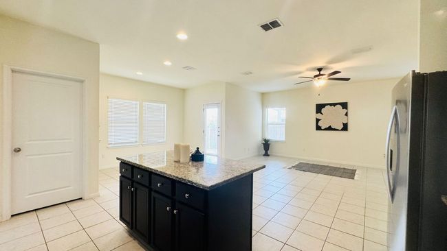 Kitchen featuring dark cabinets, freestanding refrigerator, light tile patterned flooring, recessed lighting, and a kitchen island | Image 15