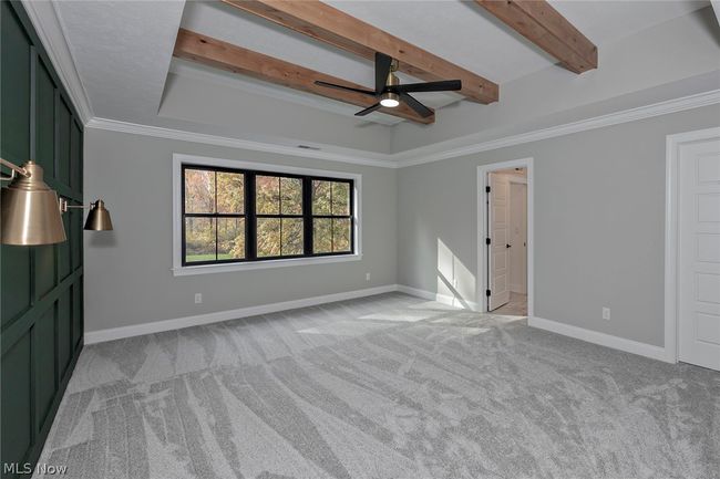 Unfurnished bedroom featuring crown molding, light carpet, a tray ceiling, beamed ceiling, and ceiling fan | Image 35