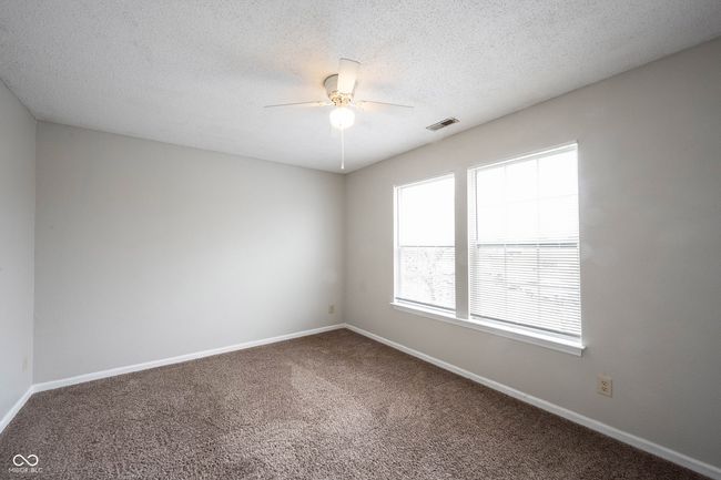 spare room with a textured ceiling, ceiling fan, carpet, baseboards, and visible vents | Image 25