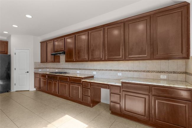 Kitchen featuring backsplash, under cabinet range hood, recessed lighting, freestanding refrigerator, and gas stovetop | Image 28