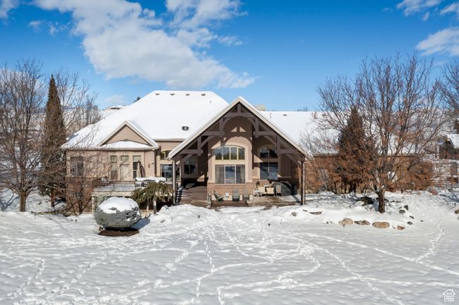 Snow covered rear of property featuring covered porch and stucco siding | Image 18