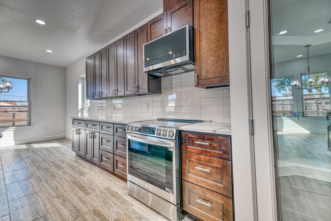 Kitchen featuring dark brown cabinetry, appliances with stainless steel finishes, a notable chandelier, and backsplash | Image 17