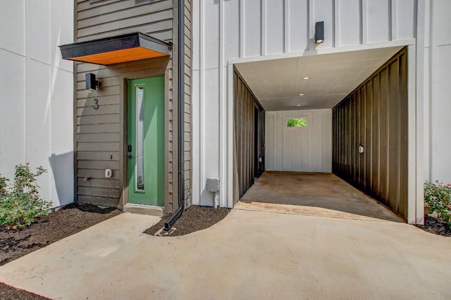 Doorway to property featuring board and batten siding, driveway, and a carport | Image 24