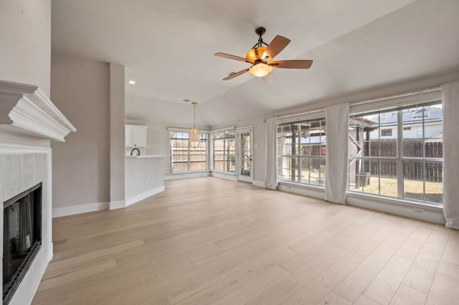 Unfurnished living room featuring a wealth of natural light, a tiled fireplace, and light wood finished floors | Image 10