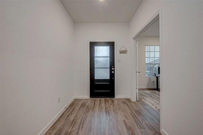 As you approach, a striking modern entry door welcomes you into an expansive, thoughtfully designed layout. At the front of the home, a sophisticated office space provides the perfect environment for productivity. The main living areas boast luxurious vinyl plank flooring, while plush carpeting adds warmth to the bedrooms. | Image 8
