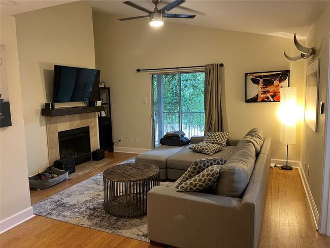 Living room featuring wood finished floors, a ceiling fan, vaulted ceiling, and a tile fireplace | Image 13
