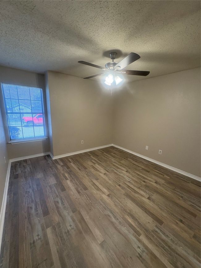 Empty room with baseboards, a textured ceiling, a ceiling fan, and dark wood finished floors | Image 13