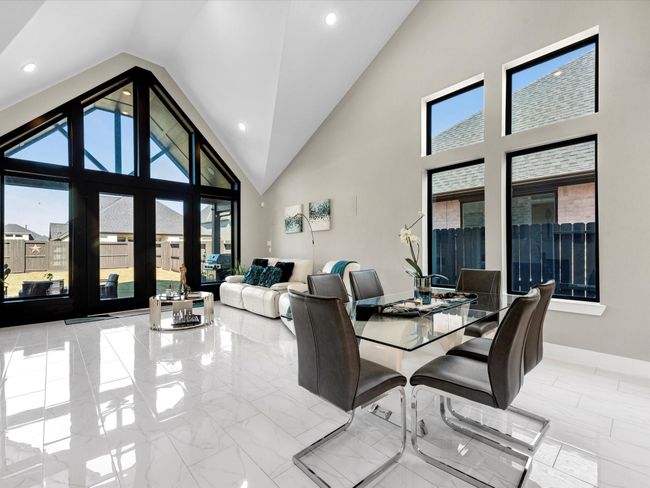 Modern and Spacious living dining areas the modern open plan with soaring vaulted ceilings and large windows that flood the space for natural light, creating a bright and inviting atmosphere. the sleek tile flooring adds a touch of elegance to the space while the neutral palette allows for versatility in decor and personal touches. | Image 17