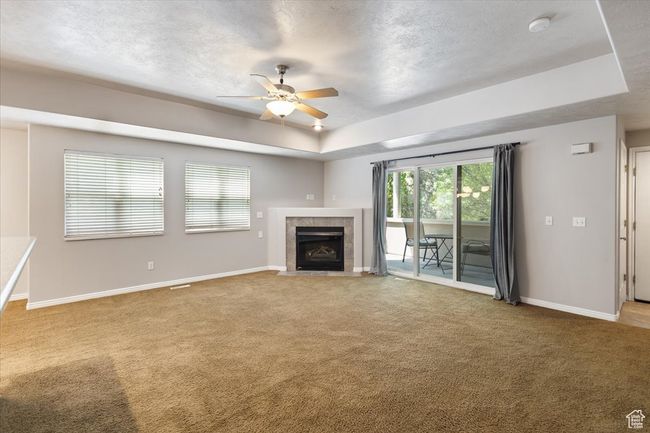 Open Living Area featuring ceiling fan, carpet flooring, a fireplace, a tray ceiling, and a textured ceiling | Image 7