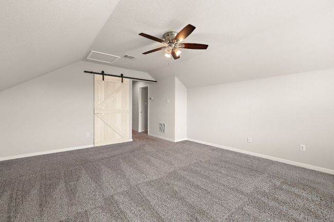 Additional living space featuring vaulted ceiling, visible vents, a ceiling fan, and carpet floors | Image 25
