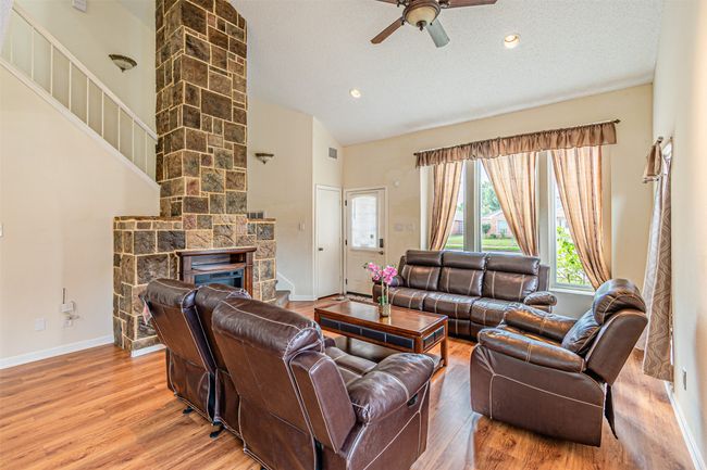 Living room with ceiling fan, plenty of natural light, light wood-style floors, a fireplace, and a textured ceiling | Image 6
