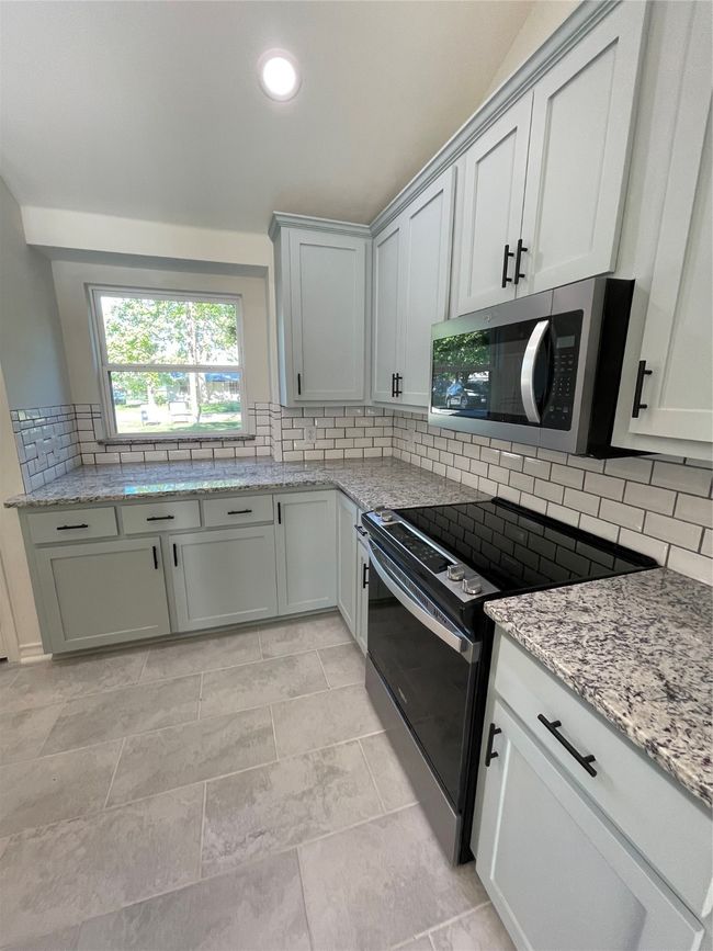 Kitchen with stove, tasteful backsplash, light stone counters, and recessed lighting | Image 20