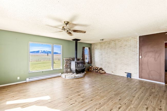 Unfurnished living room with a wood stove, a textured ceiling, and a baseboard radiator | Image 13