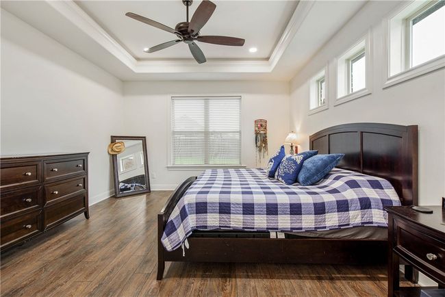 Bedroom featuring ornamental molding, a ceiling fan, wood finished floors, a raised ceiling, and baseboards | Image 15