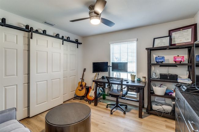 Office area with a barn door, light wood-style flooring, visible vents, and a ceiling fan | Image 20