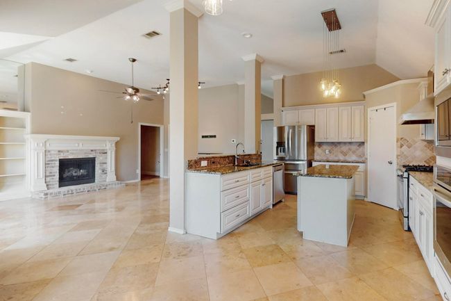 Kitchen featuring dark stone counters, ceiling fan with notable chandelier, visible vents, a sink, and stainless steel appliances | Image 11