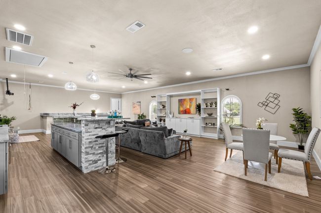 Kitchen featuring gray cabinetry, crown molding, a breakfast bar, plenty of natural light, and dark wood-style flooring | Image 23