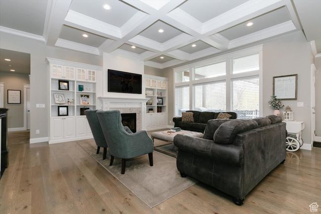 Living room featuring baseboards, light wood finished floors, a fireplace, beamed ceiling, and coffered ceiling | Image 30