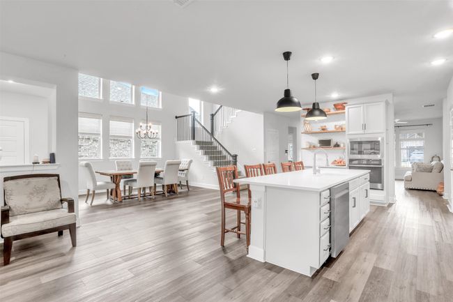 Kitchen featuring sink, appliances with stainless steel finishes, pendant lighting, a kitchen island with sink, and white cabinets | Image 14