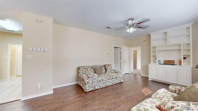 Living room with wood finished floors, a ceiling fan, visible vents, and baseboards | Image 5