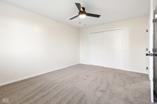 unfurnished bedroom with a closet, carpet flooring, a ceiling fan, and baseboards | Image 20