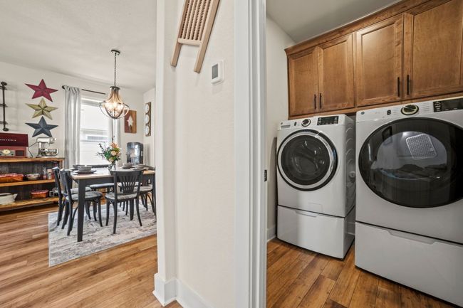 Washroom featuring washing machine and clothes dryer, an inviting chandelier, light wood-style floors, and cabinet space | Image 19