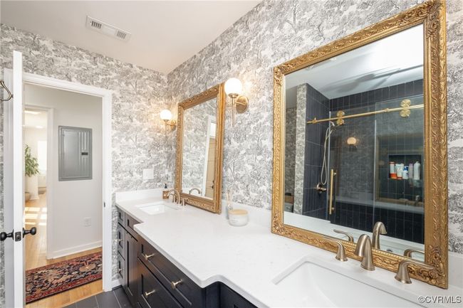 Full bathroom featuring tile patterned floors, wallpapered walls, tiled shower, vanity, and visible vents | Image 25