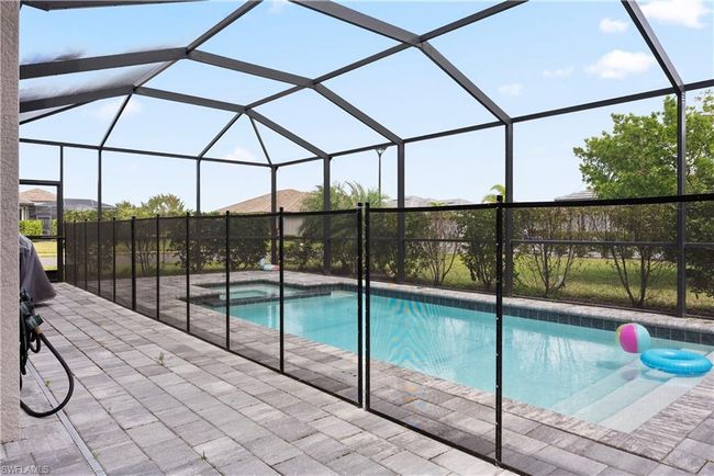 View of pool with glass enclosure, a patio, and a pool with connected hot tub | Image 37