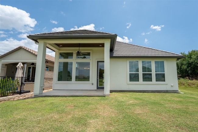 Rear view of house featuring a ceiling fan, a patio area, a lawn, stucco siding, and a tile roof | Image 32