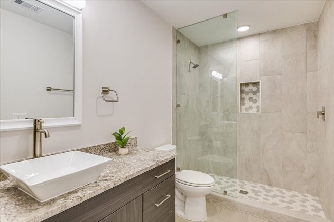 Bathroom featuring a tile shower, visible vents, toilet, and vanity | Image 16
