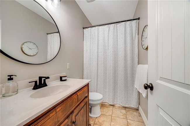 Main level bathroom with tile flooring and shower over tub. | Image 19