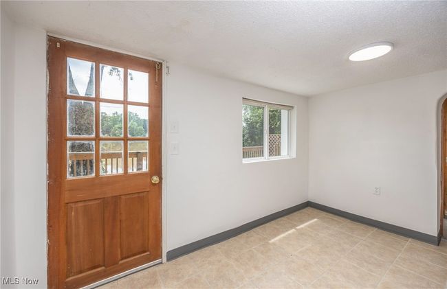 Doorway to outside featuring a textured ceiling, baseboards, and arched walkways | Image 21