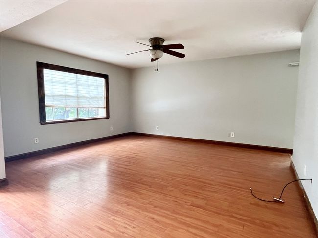 Empty room with a ceiling fan, light wood-style flooring, and baseboards | Image 15