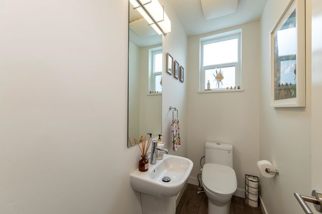 Half bathroom with toilet, wood finished floors, baseboards, and a sink | Image 11