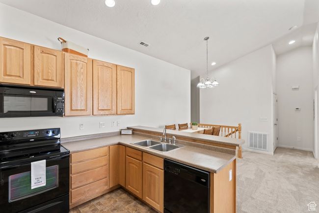 Kitchen featuring visible vents, a sink, light brown cabinetry, a peninsula, and black appliances | Image 4